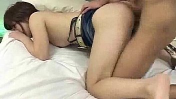 An Asian teenager is joined on the bed by a man who  from